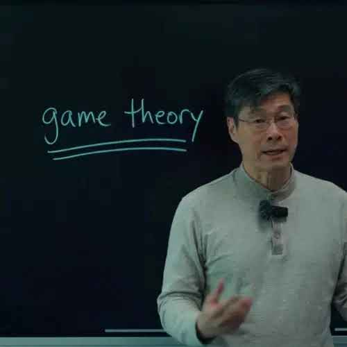 Professor at a blackboard with the words game theory written in chalk